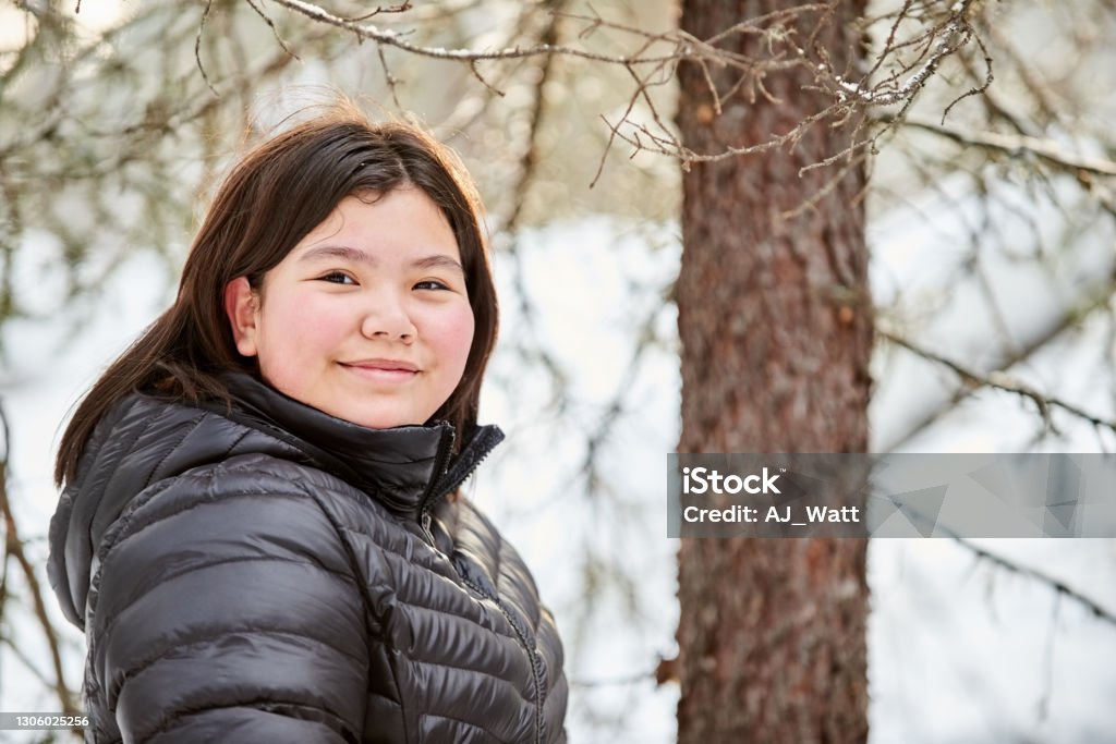 Beautiful girl in winter jacket outdoors Portrait of beautiful girl in warm jacket standing outside looking at camera and smiling Child Stock Photo