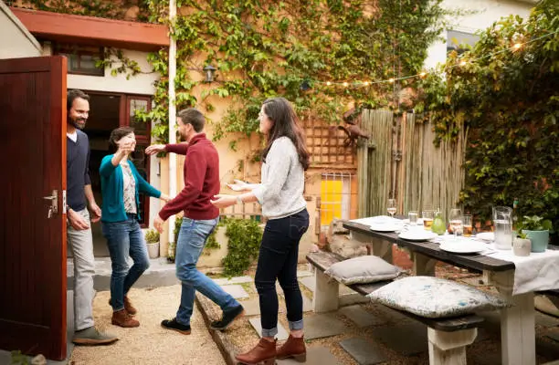 Couple welcoming friends at a dinner party in their backyard