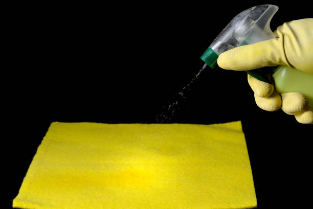 istock gloved hand throwing disinfectant liquid onto a yellow cleaning cloth 1306028396