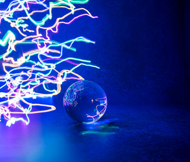 istock Neon color light trails reflected in crystal, lens ball with blue background. 1306028406