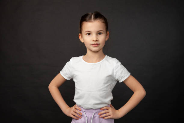 Studio portrait of 8 year old girl with brown hair back in white t-shirt on black background