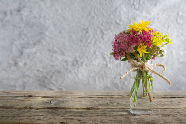 miniatur-glasflasche mit blumen auf holztisch und beton hintergrund mit sonnenlicht mit kopie space muttertag, 8 märz gruß - cut flowers white small still life stock-fotos und bilder