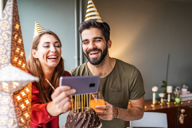 istock Romantic couple with a birthday cake, having an online celebration from home 1306030347