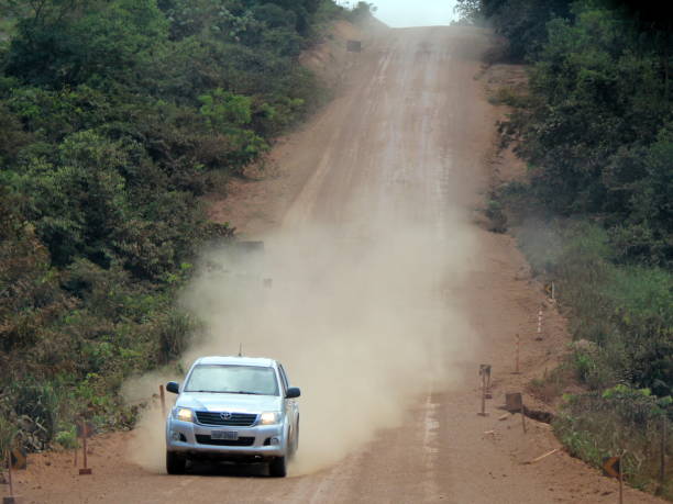 Car in a unpaved stretch of the Trans-Amazon Highway Rurópolis/Pará/Brazil - August 29, 2016: Unpaved stretch of the Trans-Amazon Highway (Transamazonica, BR-230), near of Rurópolis (state of Pará) with a car traveling through it and raising dust toyota hilux stock pictures, royalty-free photos & images