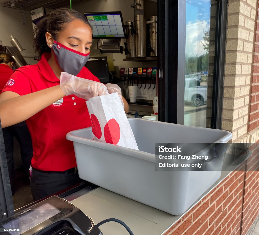 Chick-fil-A employee servicing at drive-through window McKinney, TX USA - Oct 20, 2020: Chick-fil-A employee wear mask and glove packing food for customers at the service window during covid 19 Chick-Fil-A Stock Photo