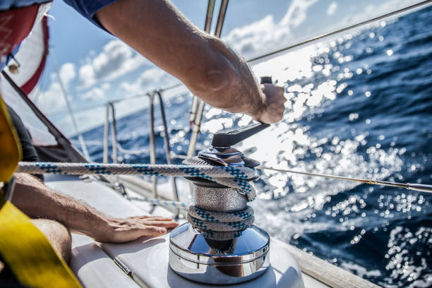 A men picking the rope Rope hauling on the winch, on the yacht. sailboat stock pictures, royalty-free photos & images