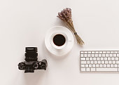 Cropped shot of the work desk, camera, coffee, lavender, keyboard.
