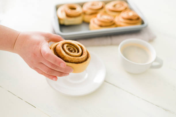 istock Woman showing a sweet roll with cinnamon and sugar 1306039786