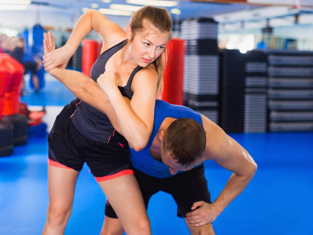 kobieta trenuje z mężczyzną na kursie samoobrony w siłowni. - conflict fighting 20s action zdjęcia i obrazy z banku zdjęć