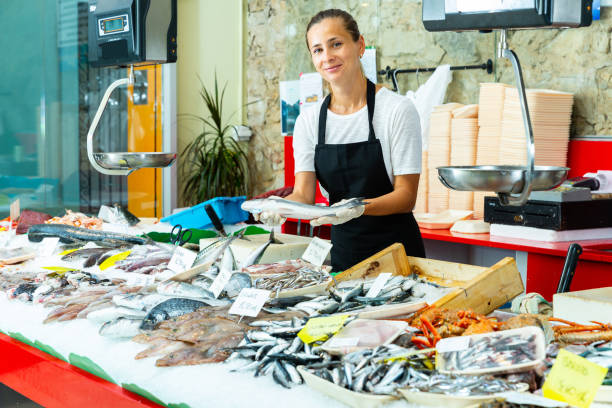 istock Female fishmonger offering fresh sea bass 1306043202
