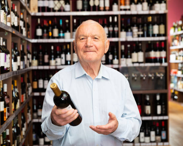 istock Attentive pensioner chooses red wine in a liquor store 1306043232