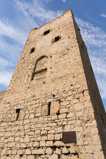 vista desde abajo de la torre clemente de la fortaleza medieval de kafa en feodosia contra el cielo azul - kafa fotografías e imágenes de stock