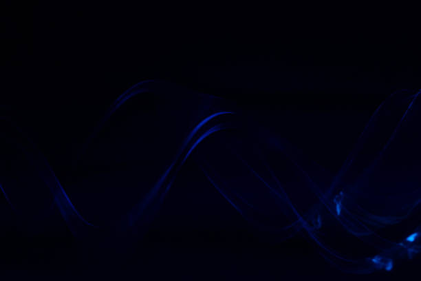 istock Abstract trailing blurred motion metallic blue ribbon wave with black background 1306046365