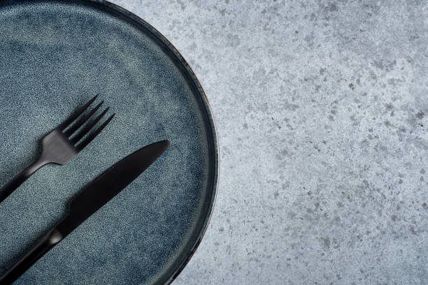 istock An empty plate and cutlery on a gray table. 1306046403