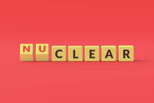 Photo of Word nuclear on yellow cubes on red background. 3d rendering