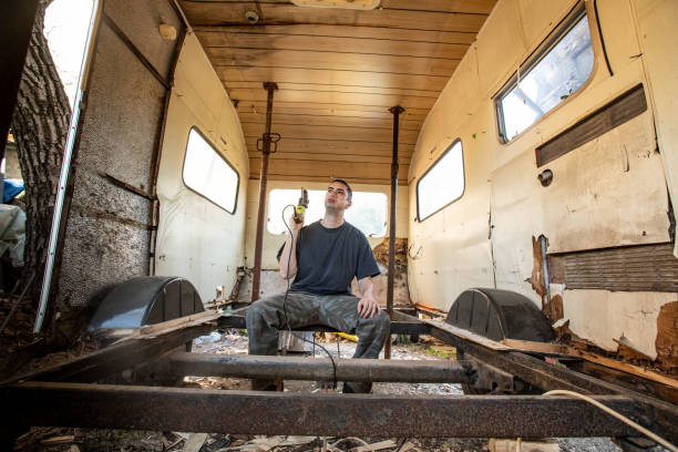 istock Young Man Sitting on Chassis of Run-down Camper Trailer 1306049495
