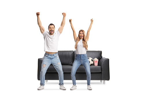 Full length portrait of a young man and woman watching football and cheering isolated on white background