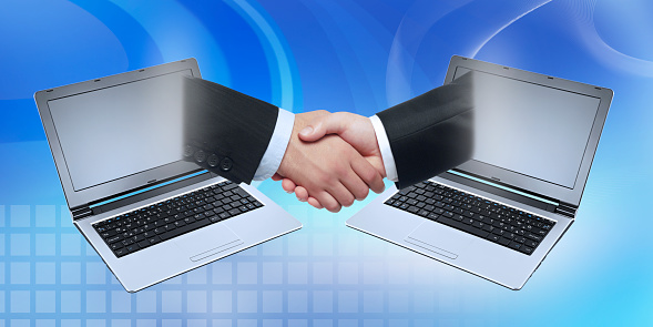 Businessmen handshaking in front of tablet computer symbolizing e-commerce