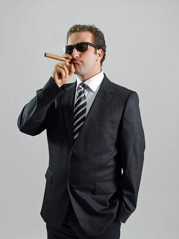 Businessman smoking cigar, posing at camera, portrait