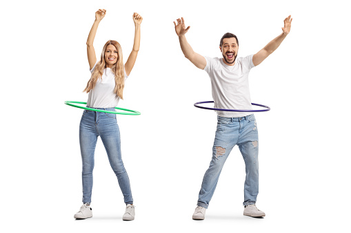 Full length portrait of a young man and woman spinning hula hoops isolated on white background