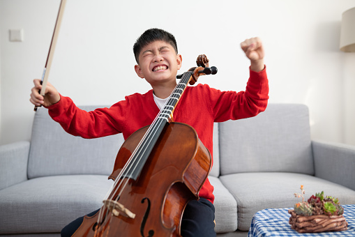 Young boy bored of practicing cello at home