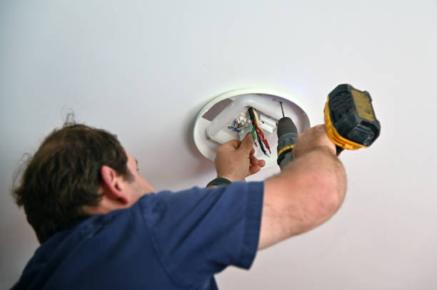 Professional electrician drilling a hole for a new  ceiling light fixture.
