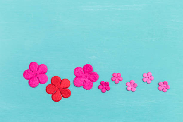 Colorful paper flower on blue background, spring season concept, greeting card background idea