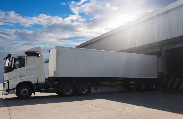 istock Cargo Trailer Truck Parked Loading at Dock Warehouse. Cargo Shipment. Induatry Freight Truck Transportation. 1306069628