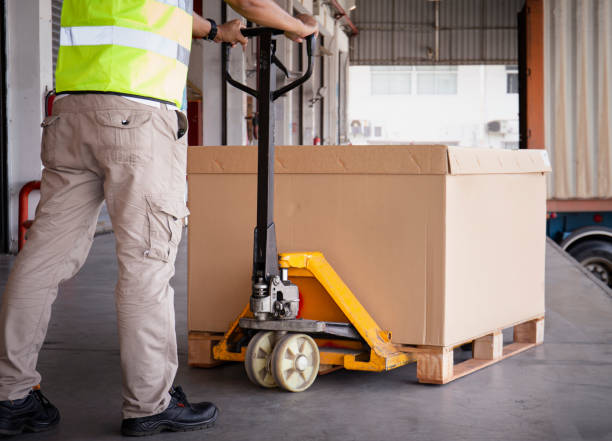istock Warehouse worker unloading haevy shipment box pallet at the warehouse. Cargo Shipment. Shipping Warehouse. 1306069629
