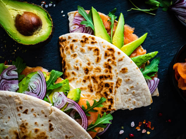 istock Italian piada wraps - piada stuffed with smoked salmon, avocado, arugula and onion on black stone plate 1306070584