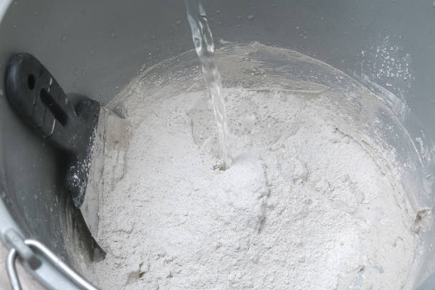 istock Mixing white plaster in a bucket with stirrer. Close-up. 1306070696