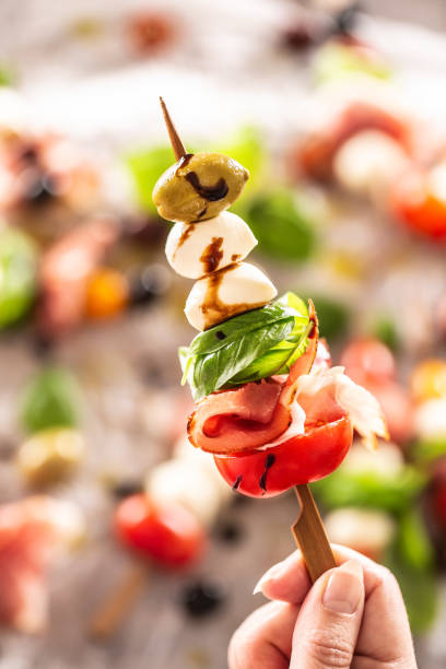 Female hand holding mini caprese skewer italian or mediterranean appetizer Female hand holding mini caprese skewer italian or mediterranean appetizer. antipasto stock pictures, royalty-free photos & images