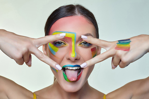 portrait of an attractive girl with bright makeup. A rainbow LGBT flag is depicted on her cheek