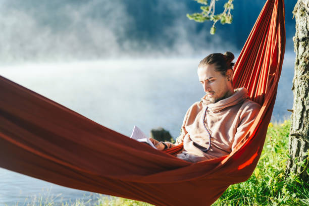 istock Man in hammock reading a book. Relaxing in the nature concept. 1306075335