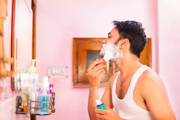 istock Indian young man looking into the mirror and applying shaving cream  beard. 1306078669