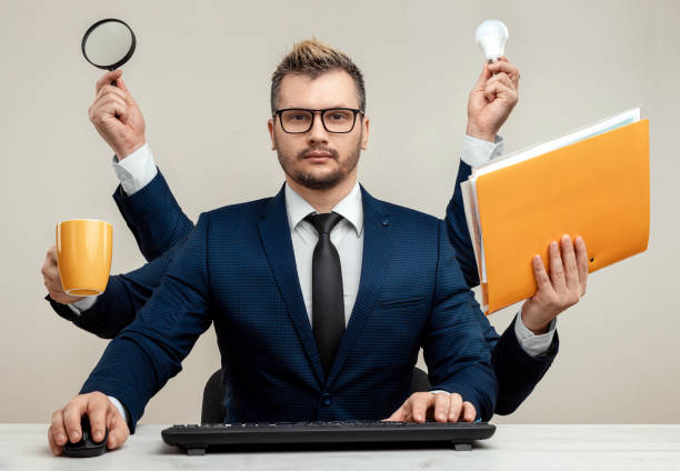 istock Businessman with many hands in a suit. Works simultaneously with several objects, a mug, a magnifying glass, papers, a contract, a telephone. Multitasking, efficient business worker concept. 1306079927