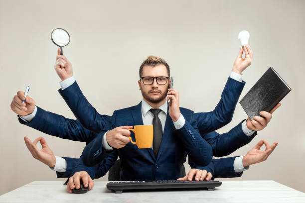 istock Businessman with many hands in a suit. Works simultaneously with several objects, a mug, a magnifying glass, papers, a contract, a telephone. Multitasking, efficient business worker concept. 1306079945
