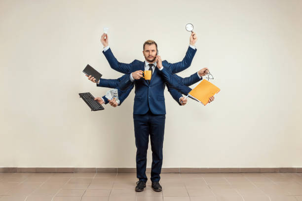 istock Businessman with many hands in a suit. Works simultaneously with several objects, a mug, a magnifying glass, papers, a contract, a telephone. Multitasking, efficient business worker concept. 1306079946