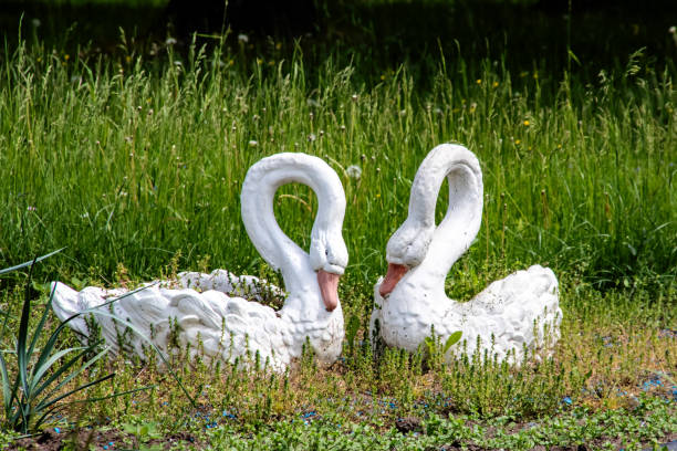istock Sculpture of two swans on a flowerbed 1306081745