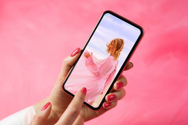 Person holding phone and looking at woman dancing in video posted on social media Person browsing social media and looking at posted video with woman dancing youtube stock pictures, royalty-free photos & images