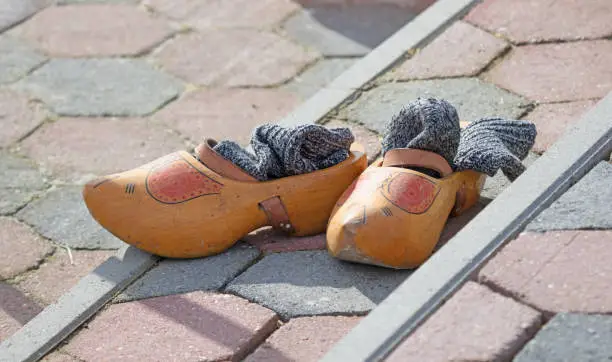 Old yellow wooden shoes with old socks at the side of a frozen river - Owner is ice skating - Common spectacle in dutch winter period