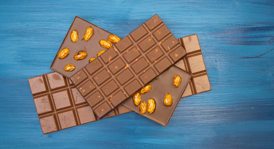 a lot of different tasty chocolate bars on blue background