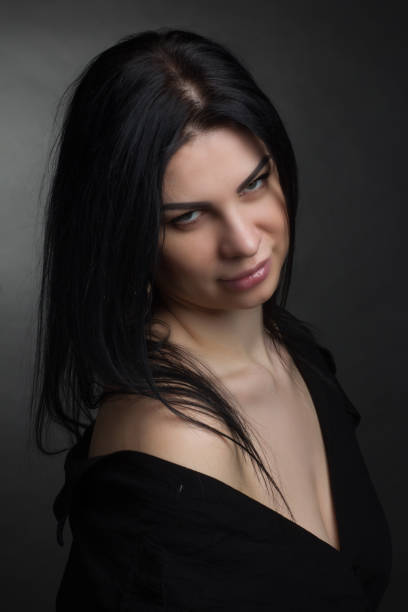 Studio portrait of a brunette in black clothes on a dark background