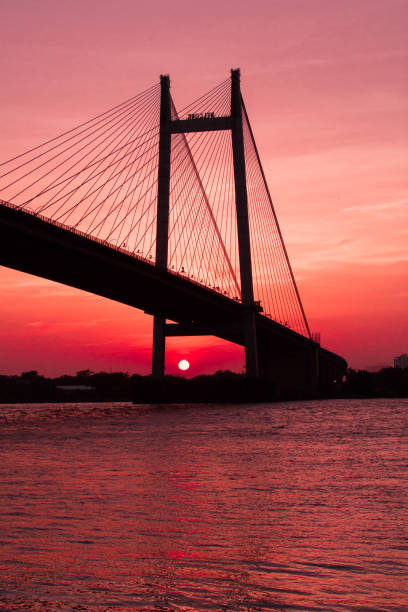 una imagen de la puesta de sol por el ganges, también conocido como ganga en calcuta con el famoso puente vidyasagar en marco - bengala del oeste fotografías e imágenes de stock