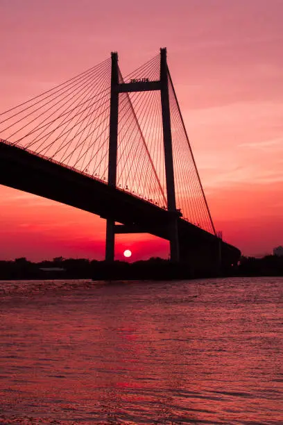 An image of sunset by the Ganges, also known as Ganga in Kolkata with the famous Vidyasagar Bridge in frame