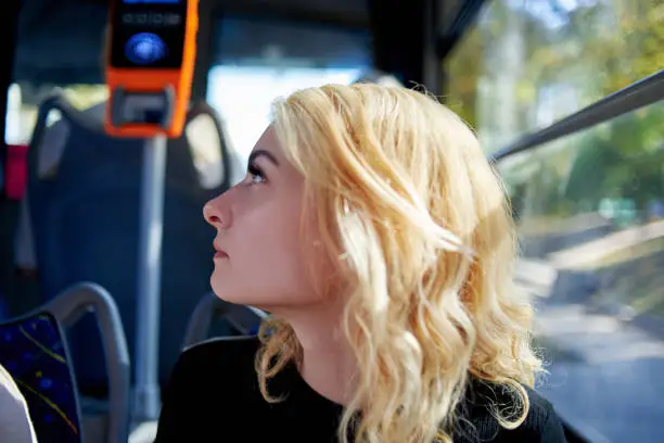 Portrait of a beautiful young woman who rides in a trolleybus near the window.
