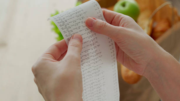 istock Close-up man looking a check from a supermarket. Expense tracking and budgeting 1306089142