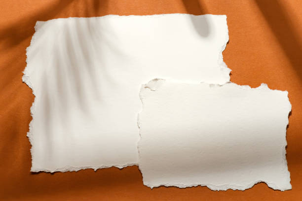 istock ripped white paper note on white background with shadow on brown background 1306089268
