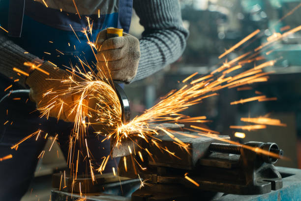 istock Locksmith in special clothes and goggles works in production. Metal processing with angle grinder. Sparks in metalworking 1306090922