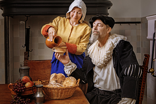 Portrait of a beautiful historical dutch noble man and woman wearing historically correct outfits in a typical townhouse drawing room